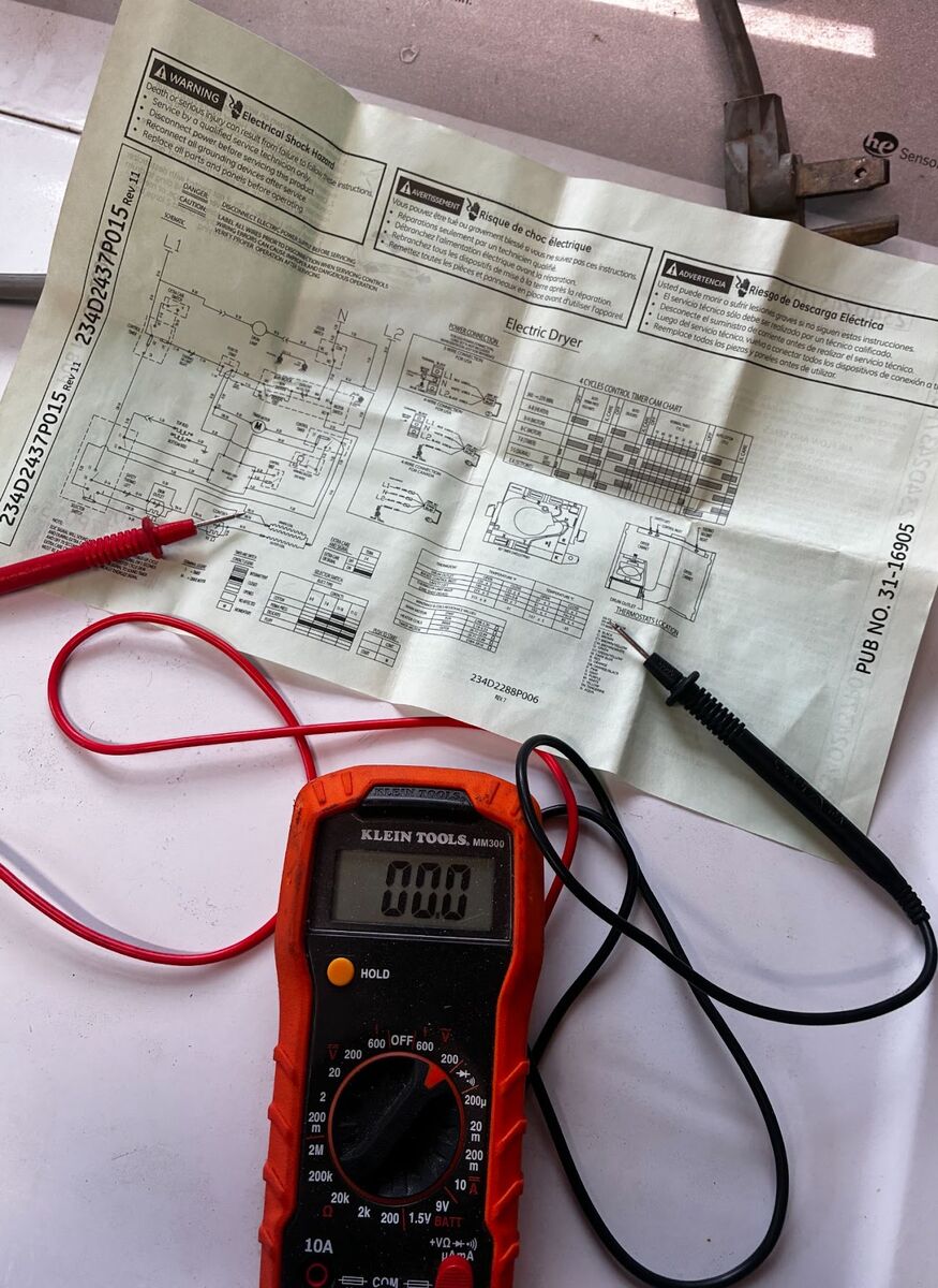 Cross-referencing the appliance's wiring diagram while testing components.